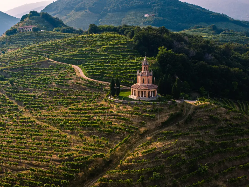 Colline coperte di vigneti a Farra di Soligo, nel Trevigiano, con una piccola chiesa sulla cima