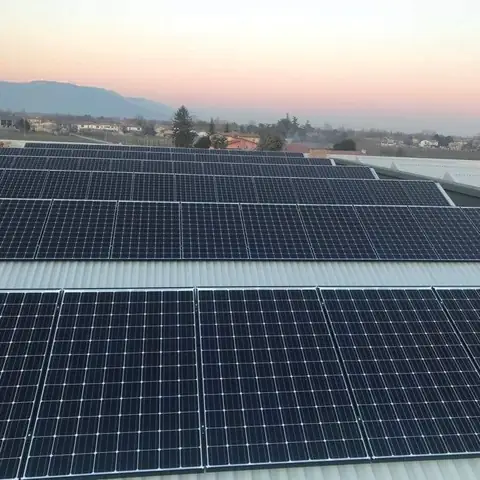 Moduli su una copertura in lamiera al tramonto, con le colline e il paese
