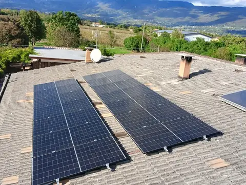 Due file di moduli neri sulle tegole di cemento, con le colline e le montagne sullo sfondo