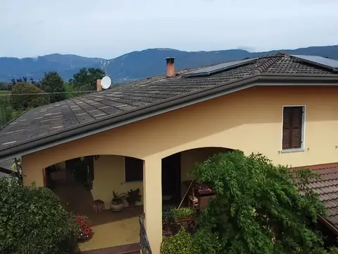 Casa con il portico ad archi e i moduli sulla falda, con le montagne sullo sfondo