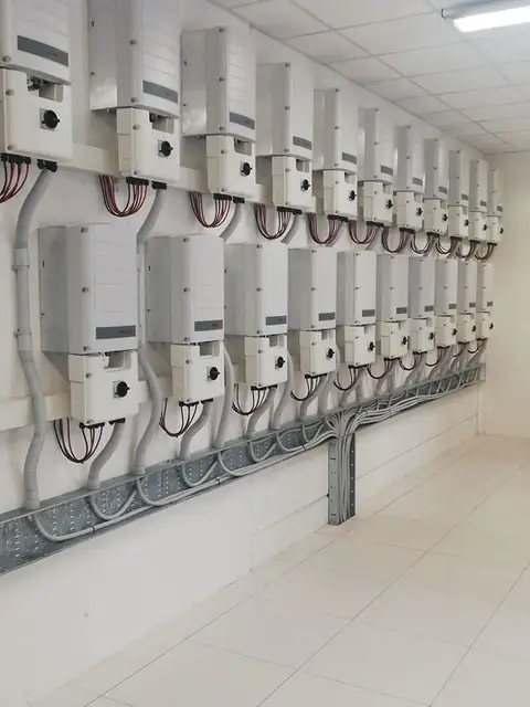 Una parete di inverter in due file con le canaline dei cavi in un locale tecnico