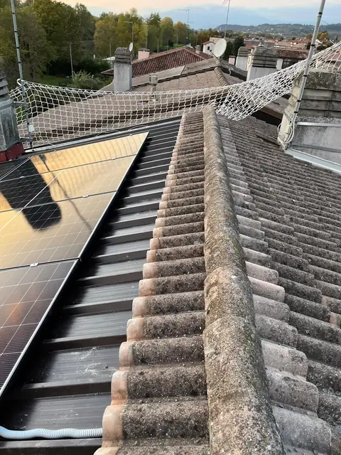 Moduli posati su un tetto in coppi con la rete di sicurezza e la linea vita