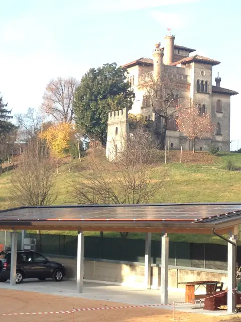 Pensilina con la copertura di moduli, sotto una villa con la torre sulla collina