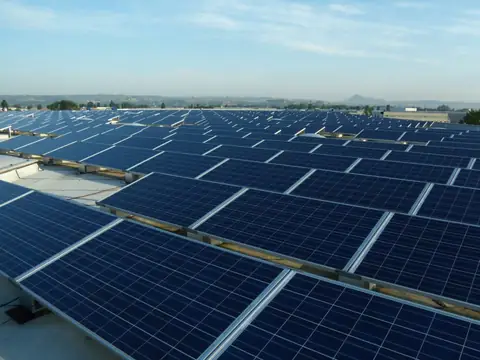Grande impianto su un tetto piano, decine di file di moduli con la campagna intorno