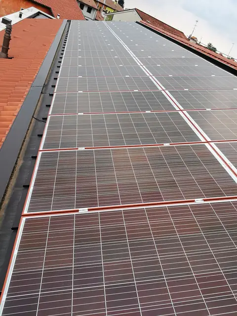 Moduli fotovoltaici che coprono un'intera falda, tra i tetti in tegole del paese